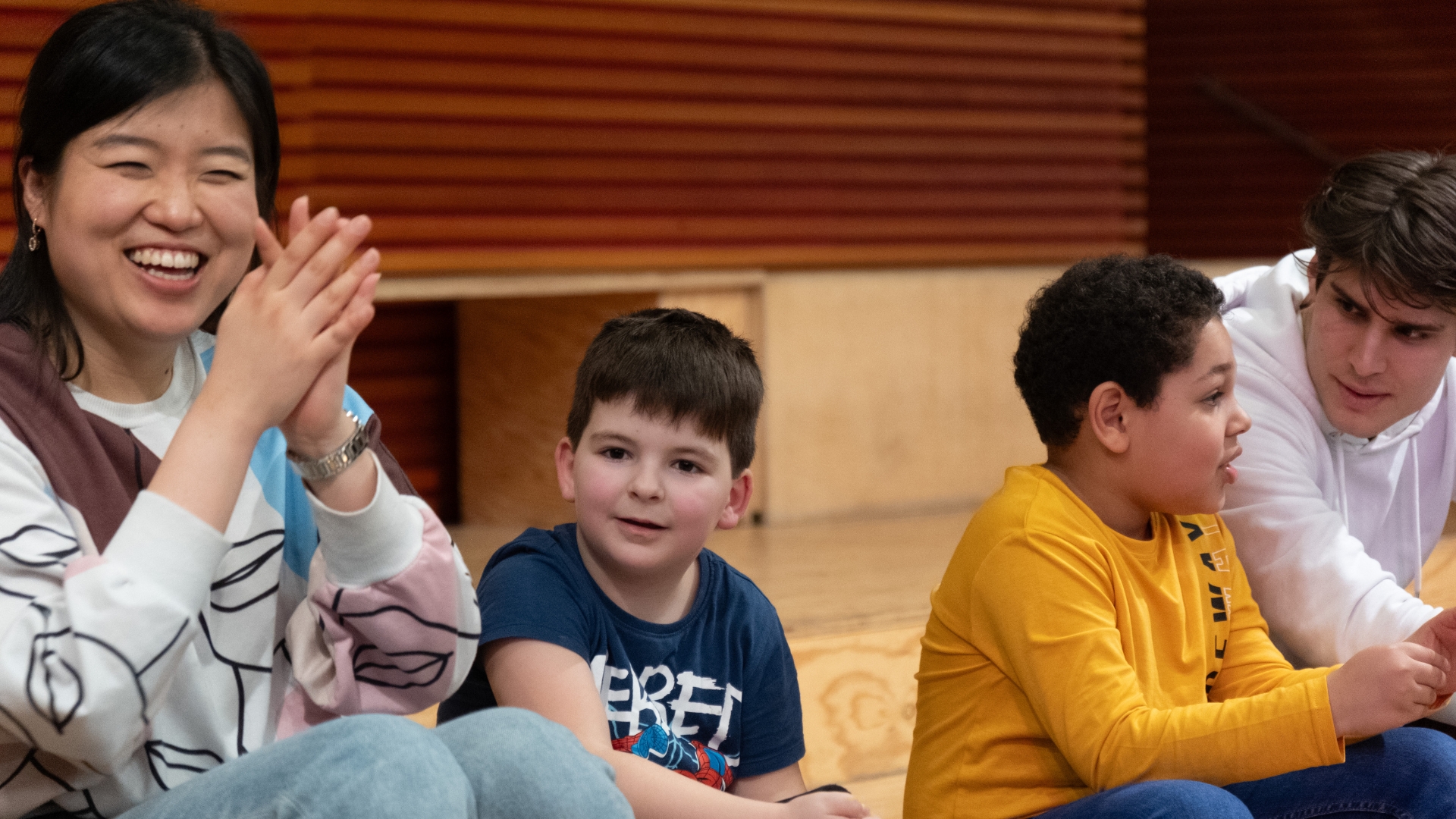 Erwachsene und Kinder sitzen auf einer Bank und lachen